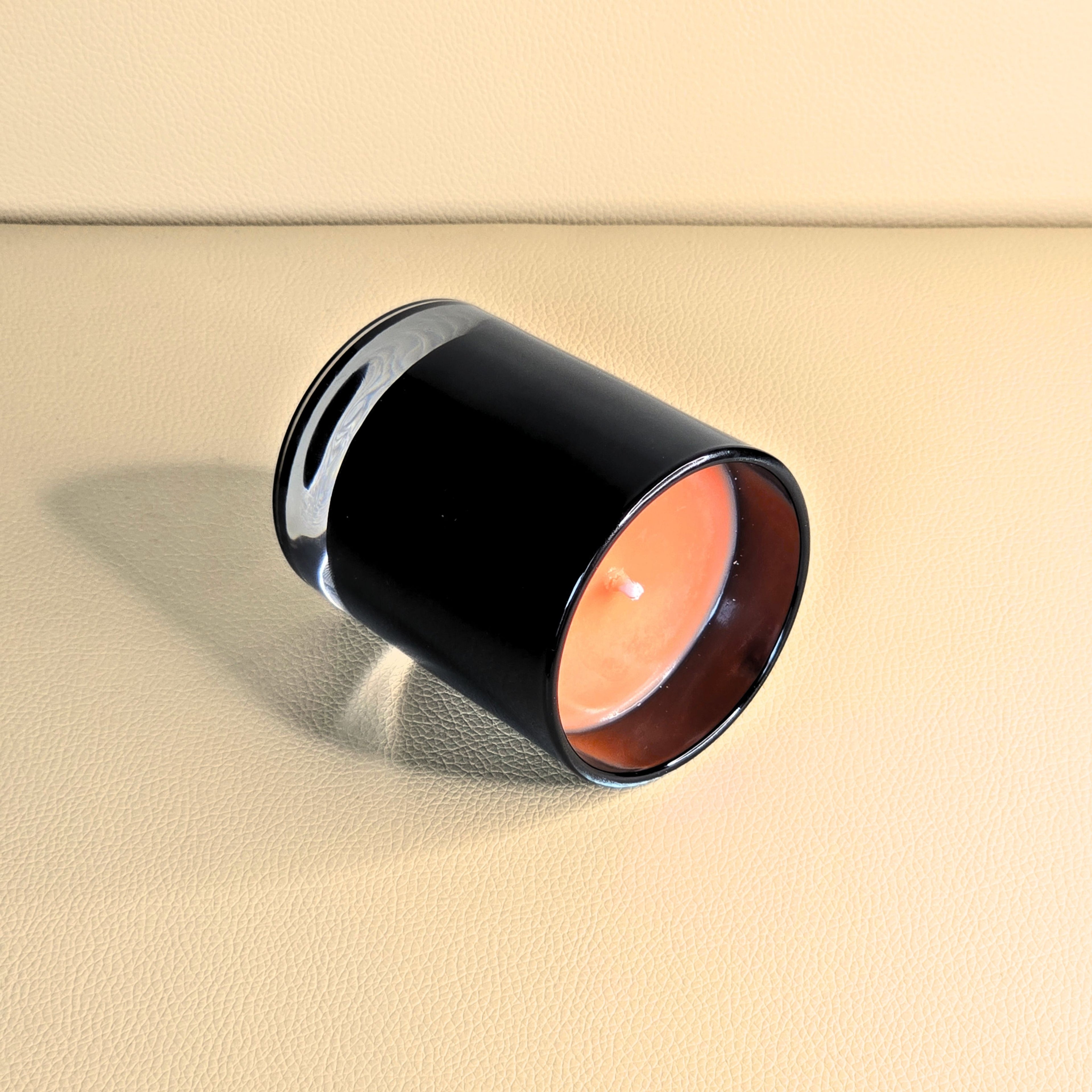 Side view of handcrafted amber candle in luxury black vessel.