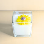 Front view of white floral soy candle featuring a bright yellow flower design.
