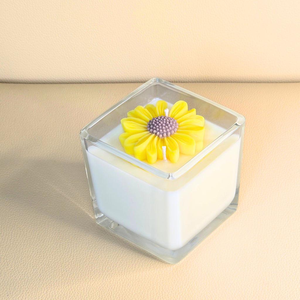 Handcrafted white soy candle in clear glass with a sculpted yellow flower top – Wicks of Intention.