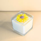 Handcrafted white soy candle in clear glass with a sculpted yellow flower top – Wicks of Intention.