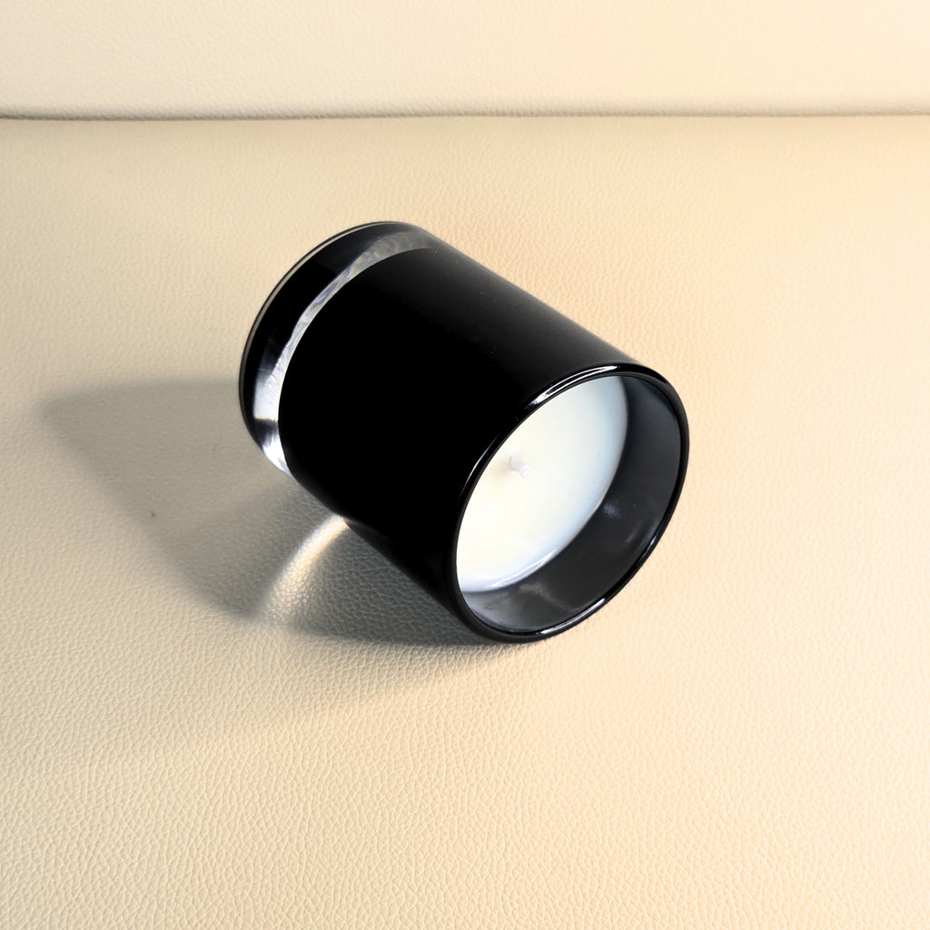 Side angle of handcrafted white candle in premium black vessel.